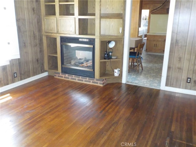 2698 Fremontia Dr, San Bernardino, CA 92404 - unfurnished living room with wood finished floors, wood walls, a brick fireplace, and baseboards