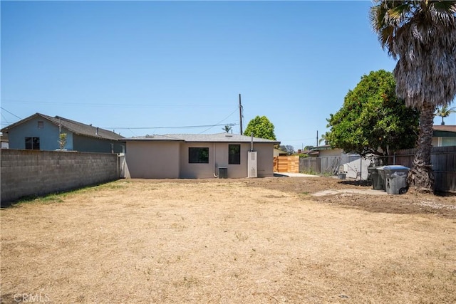 back of house with a fenced backyard, stucco siding, and central AC unit
