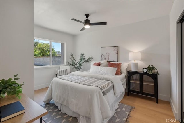 bedroom featuring baseboards, wood finished floors, and a ceiling fan