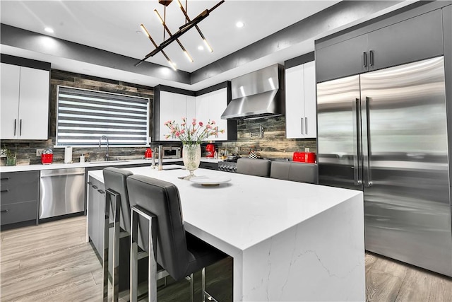 9218 Encino Ave, Northridge, CA 91325 - kitchen featuring stainless steel appliances, wall chimney range hood, a sink, backsplash, and an island with sink