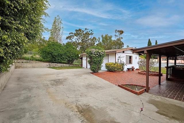 view of front of house featuring an outdoor structure, concrete driveway, fence, and stucco siding