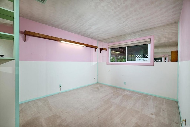 empty room with carpet, a textured ceiling, and baseboards