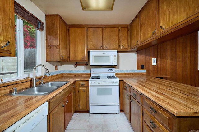 kitchen with white appliances, a sink, brown cabinetry, and butcher block counters
