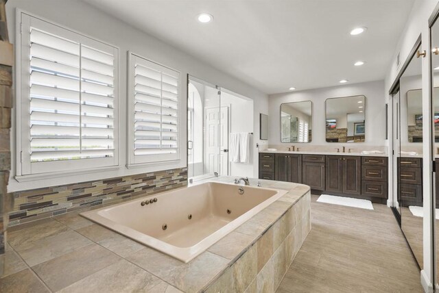 full bath with a jetted tub, double vanity, and recessed lighting