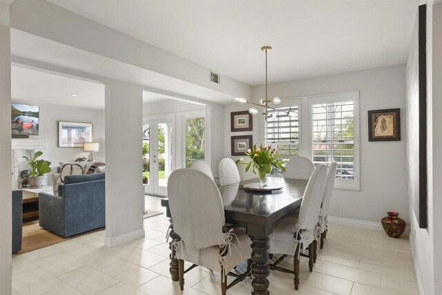 dining room with plenty of natural light, light tile patterned floors, baseboards, and a chandelier