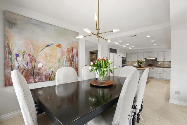 dining area with a chandelier, baseboards, a raised ceiling, and recessed lighting