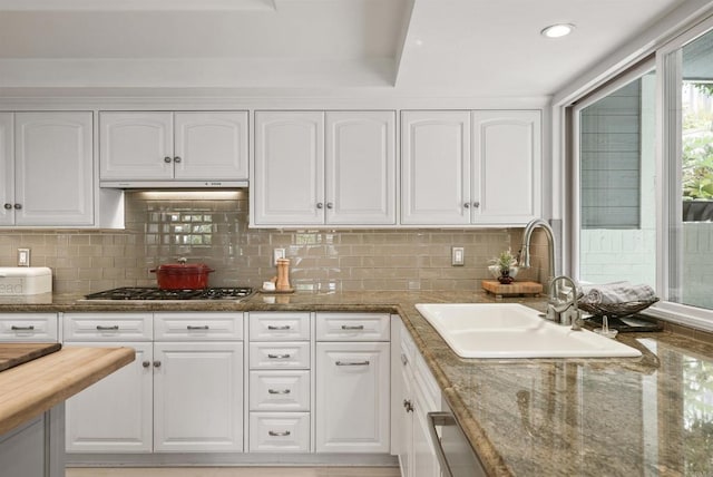 kitchen with stainless steel gas stovetop, a sink, white cabinets, dark stone counters, and recessed lighting
