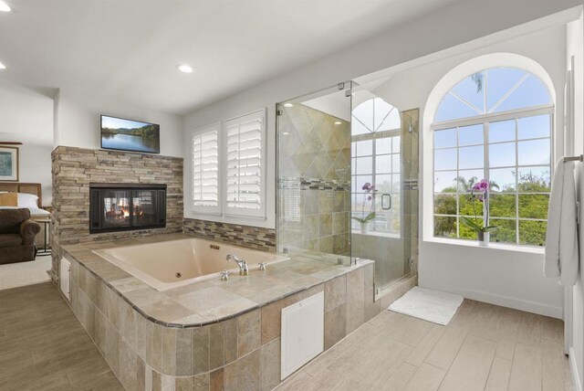 bathroom featuring recessed lighting, a stall shower, a multi sided fireplace, a tub with jets, and baseboards