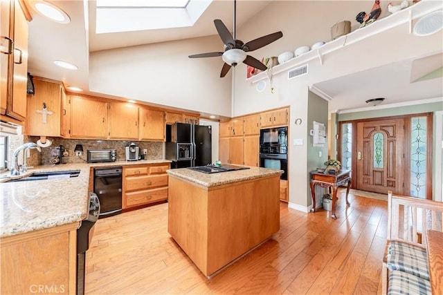 kitchen featuring a sink, black appliances, ceiling fan, backsplash, and light wood finished floors