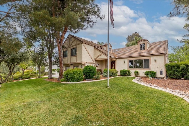 tudor house with stucco siding and a front yard