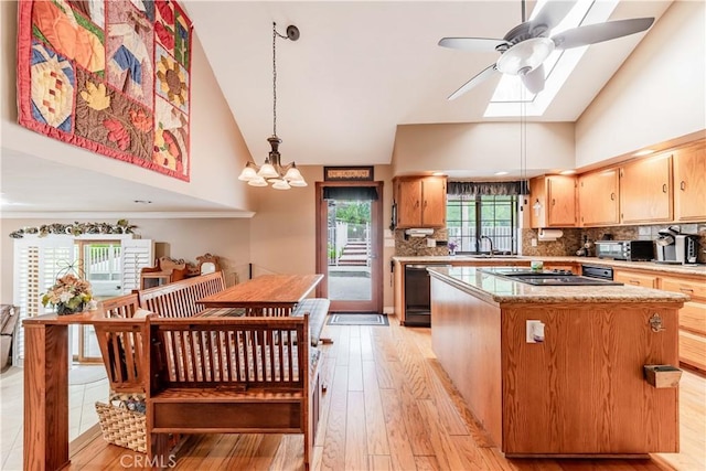 kitchen featuring black appliances, high vaulted ceiling, a kitchen island, ceiling fan, and a skylight