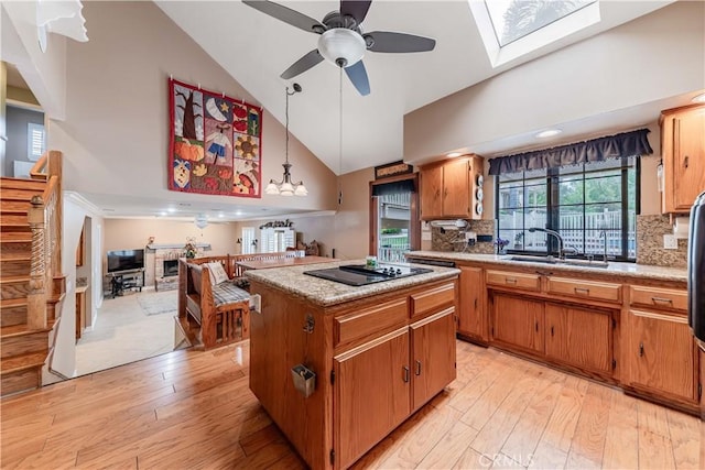kitchen with high vaulted ceiling, a skylight, a center island, light wood finished floors, and ceiling fan