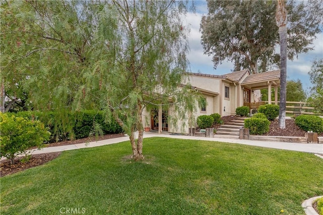 view of front of property featuring a front lawn, stucco siding, and stairs