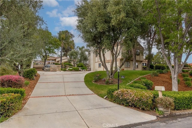 view of property's community featuring a yard and concrete driveway