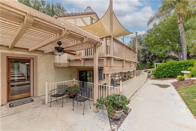 entrance to property featuring a pergola, ceiling fan, a patio, and stucco siding