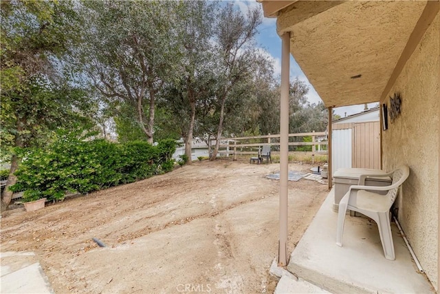 view of patio featuring fence and view of wooded area