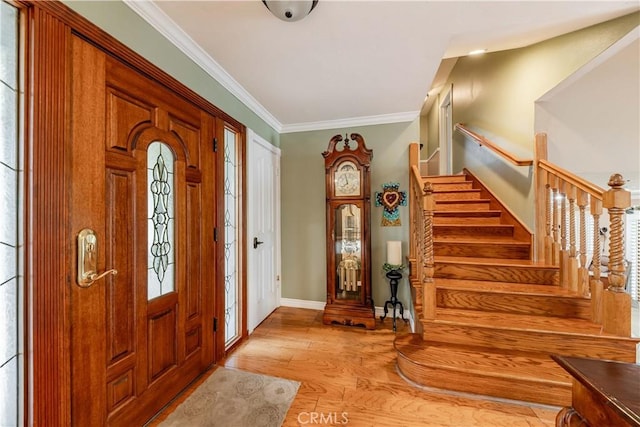 foyer featuring baseboards, stairs, light wood-type flooring, and ornamental molding