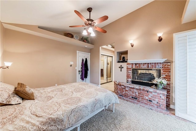 carpeted bedroom with vaulted ceiling, a fireplace, ceiling fan, and a closet