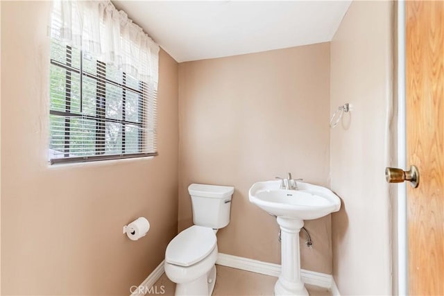 half bath featuring toilet and baseboards