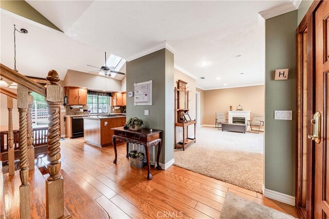kitchen with crown molding, light wood-type flooring, a fireplace, open floor plan, and baseboards