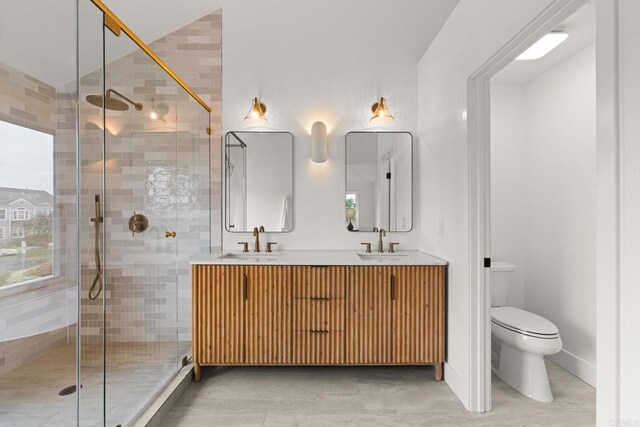 bathroom featuring a stall shower, toilet, and double vanity
