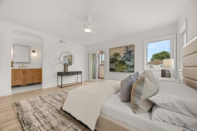 bedroom featuring light wood-style floors, multiple windows, and ensuite bathroom
