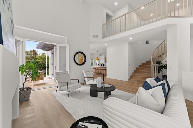 living room with a high ceiling, light wood finished floors, stairway, baseboards, and recessed lighting