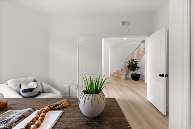 sitting room featuring light wood-type flooring, stairway, and baseboards