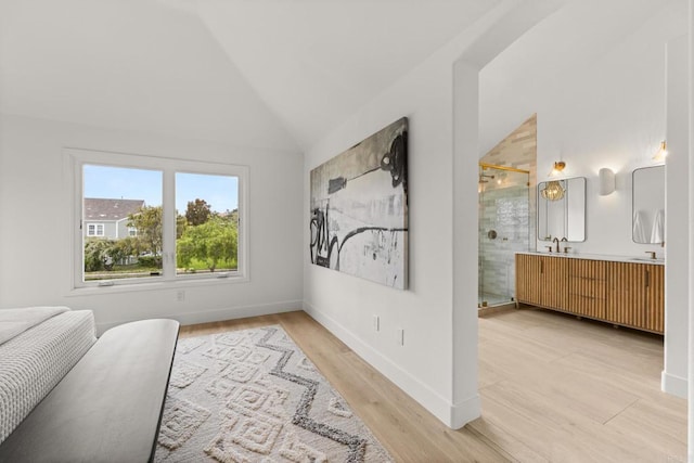 bedroom featuring vaulted ceiling, light wood-style flooring, and baseboards