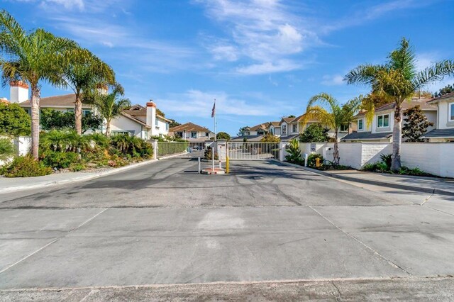 view of concrete street with a residential view, a gate, sidewalks, a gated entry, and curbs