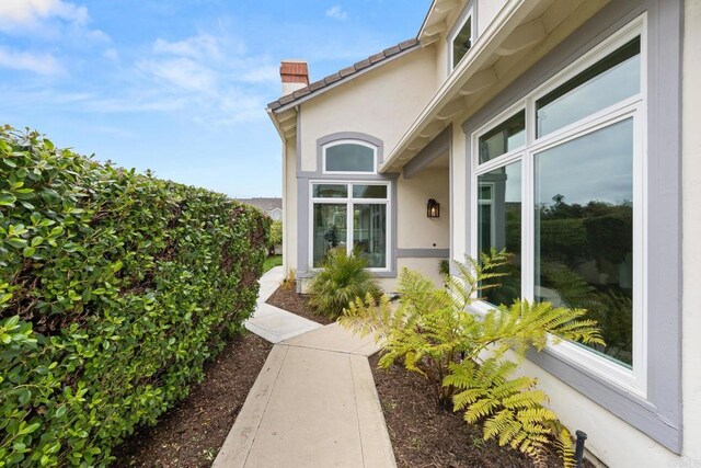 doorway to property with stucco siding and a chimney