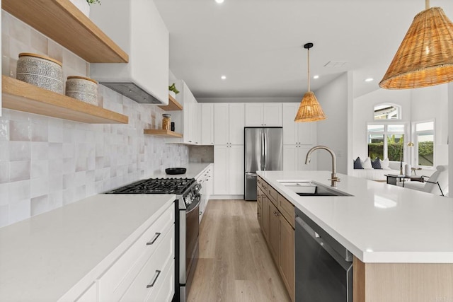 kitchen with appliances with stainless steel finishes, a sink, open shelves, light wood-style flooring, and light countertops