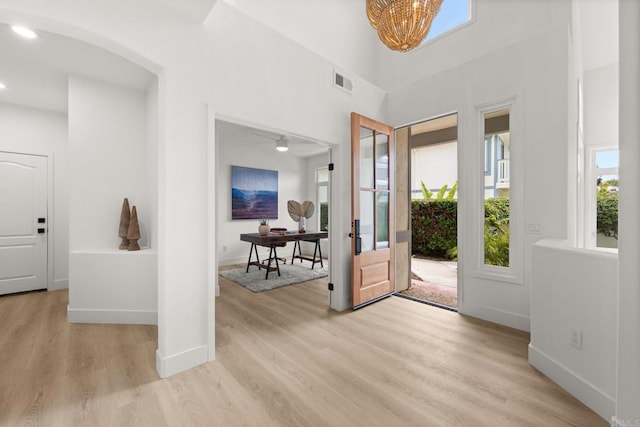 entrance foyer featuring light wood-style floors, baseboards, a chandelier, arched walkways, and recessed lighting