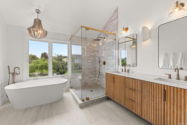 bathroom featuring a shower stall, double vanity, a freestanding tub, a chandelier, and lofted ceiling