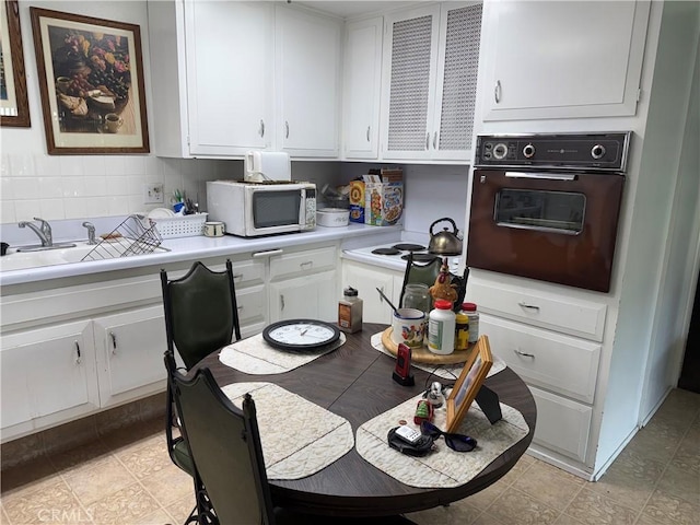 kitchen featuring wall oven, light countertops, white cabinets, and tasteful backsplash