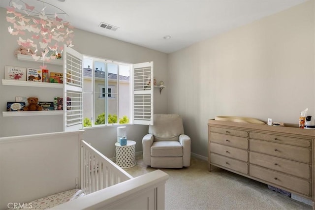 bedroom featuring a nursery area and light colored carpet
