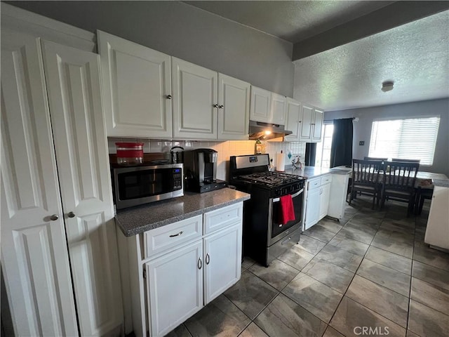 527 E King St, Rialto, CA 92376 - kitchen with stainless steel appliances, under cabinet range hood, white cabinetry, a textured ceiling, and tasteful backsplash