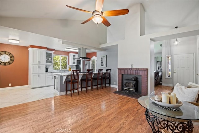 9 Benton Ave, Chico, CA 95973 - living area with baseboards, a wood stove, high vaulted ceiling, a ceiling fan, and light wood-style floors