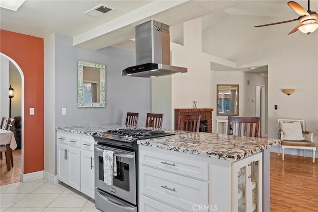 9 Benton Ave, Chico, CA 95973 - kitchen featuring island exhaust hood, gas stove, light stone countertops, a ceiling fan, and arched walkways