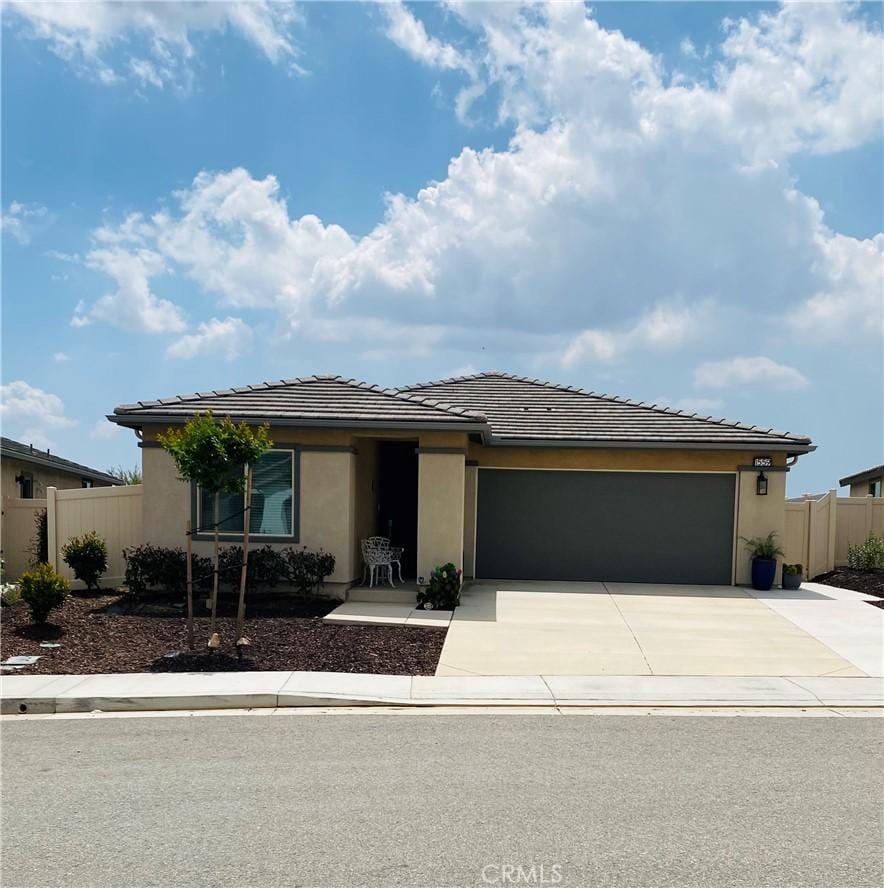 view of front facade with fence, concrete driveway, a garage, and stucco siding