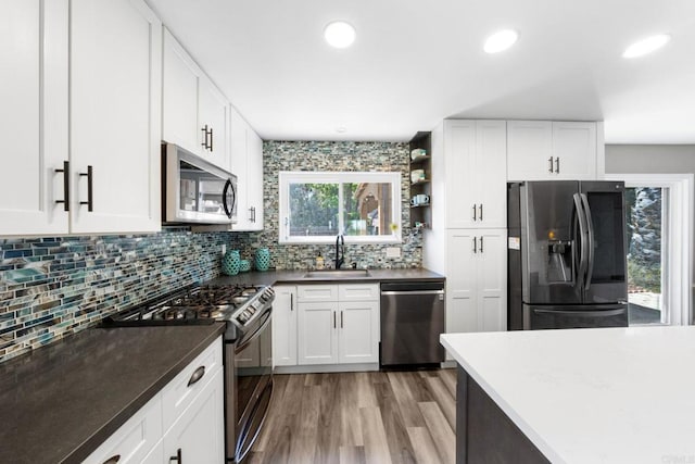 3221 Camarillo Ave, Oceanside, CA 92056 - kitchen with appliances with stainless steel finishes, a sink, backsplash, wood finished floors, and white cabinets