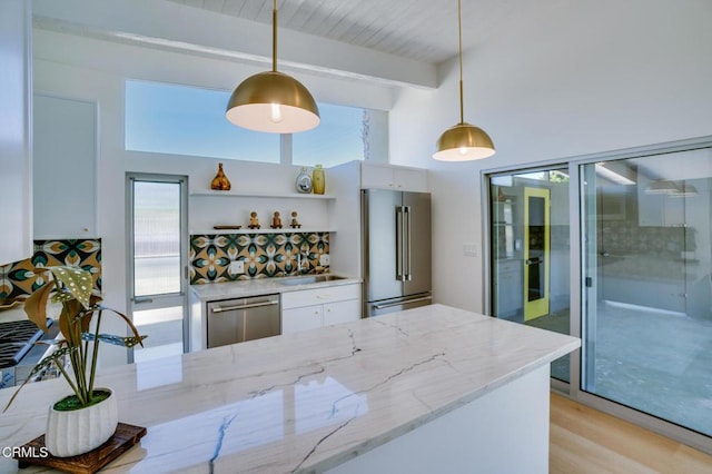 bar with appliances with stainless steel finishes, a sink, beam ceiling, decorative light fixtures, and a towering ceiling