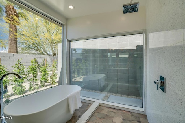 full bathroom featuring a soaking tub, a shower stall, recessed lighting, and tile walls