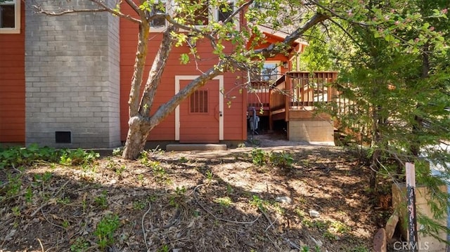 back of property featuring a deck, brick siding, and crawl space