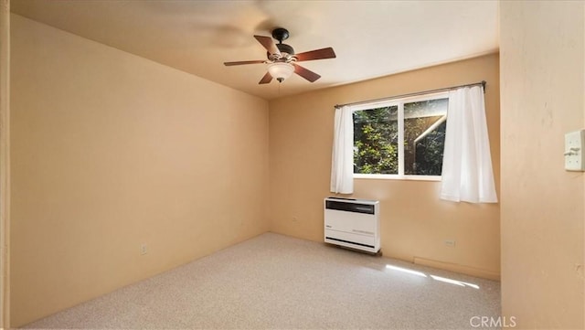 empty room featuring heating unit, ceiling fan, and carpet floors