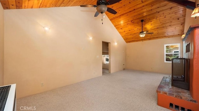 unfurnished living room with a wood stove, a ceiling fan, carpet flooring, wooden ceiling, and high vaulted ceiling
