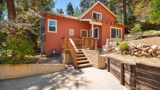 back of property with a chimney, a wooden deck, and stairs