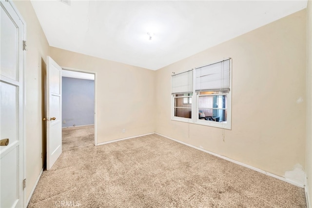 unfurnished room featuring light colored carpet and baseboards
