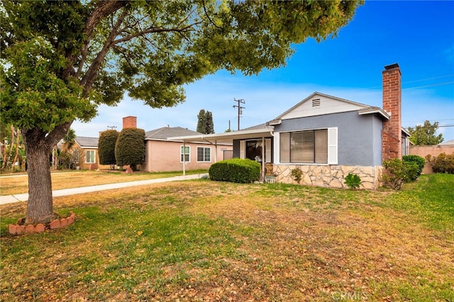 single story home featuring a front yard, stucco siding, and a chimney