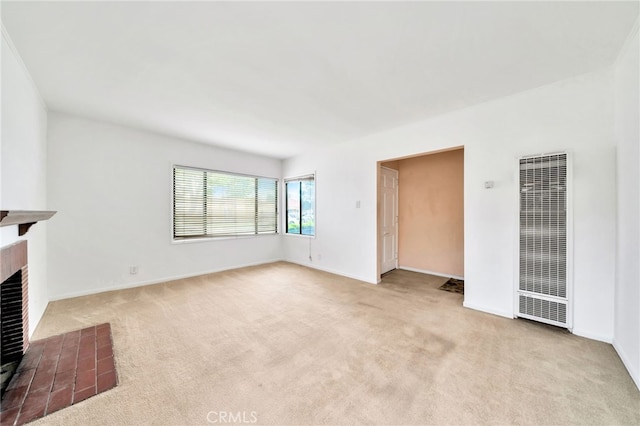 unfurnished living room with a heating unit, carpet floors, a tile fireplace, and baseboards